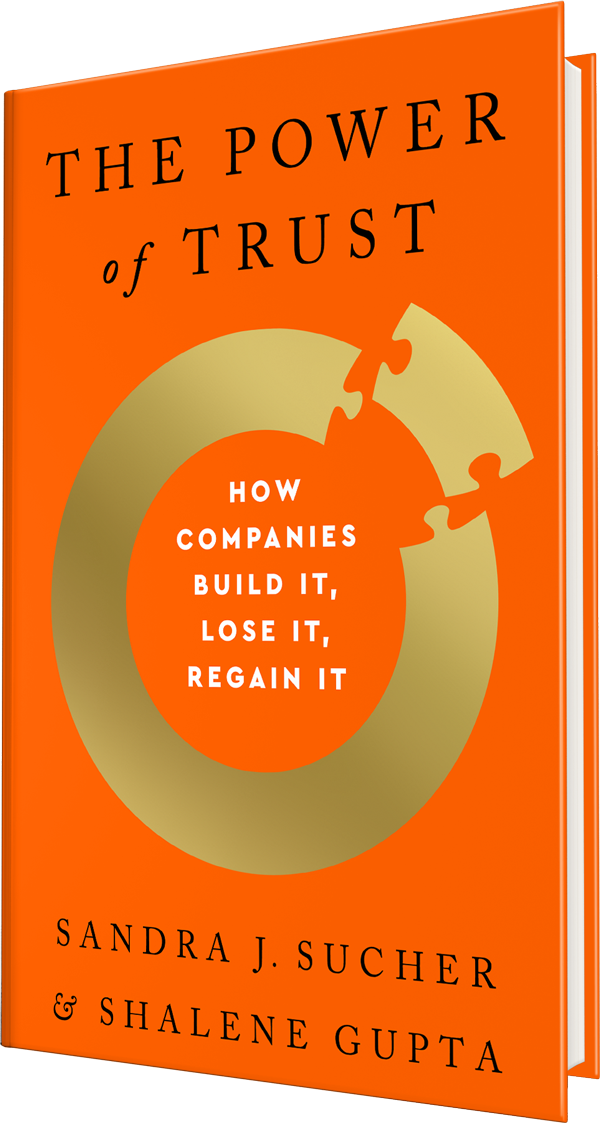 Orange hardcover book cover for The Power of Trust, with a gold ring and puzzle piece